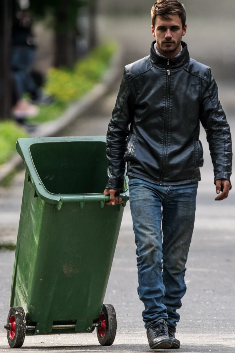 Man pulling a trash bin back to its place by your house.